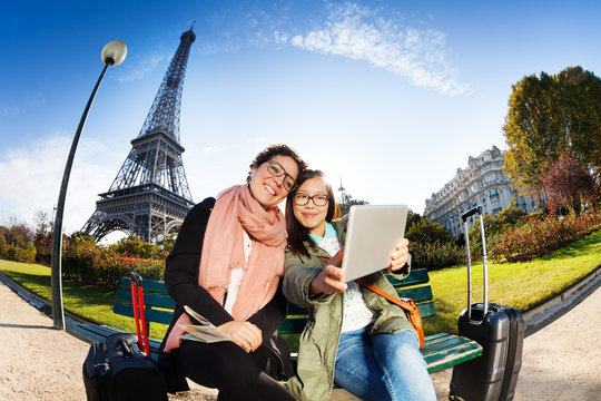 Two friends using a tablet taking selfie in Paris