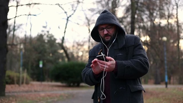 Mature man listening to music on cellphone in park
