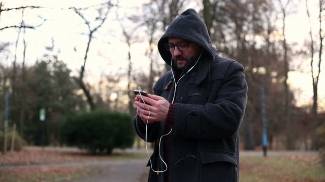 Male man listening to music on cellphone in park
