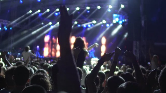 Rock concert audience raising hands and applauding to cool band, slow motion