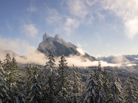 Breathtaking Scenic View Across Mountain Valley with Sun Lit Rolling Fog by Snowy Peaks