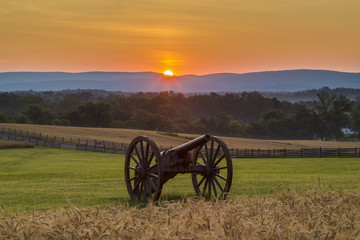 Sun rising behind artillery near a wheat field at Antietam Natio