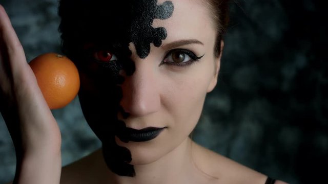 4k Shot of a Woman with Halloween Make-up Rolling an Orange on Face