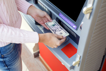 Obraz premium Woman hand withdrawing money from outdoor bank ATM