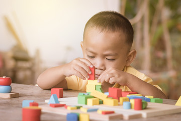 Boy intend to build construction with wooden color blocks.