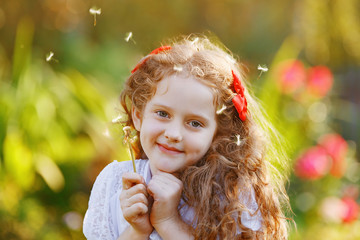 Cute little girl with dandelion flower in a spring park. Happy childhood concept.