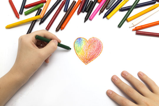 Picture of hands drawing heart with crayon taken from above