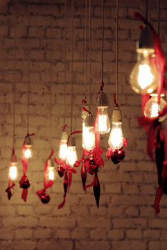 Decorative edison style light bulbs with valentines day decor and a brickwall on the background. 