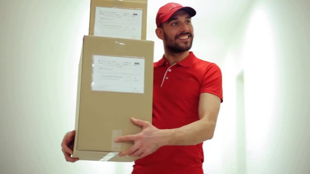 happy man with parcel boxes walking along corridor