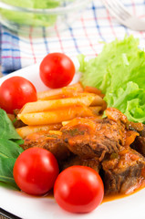 Dish of beef stew with pasta penne and cherry tomatoes