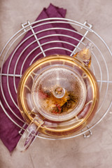 Glass teapot with tea on cooling rack. Concrete background. Top view.