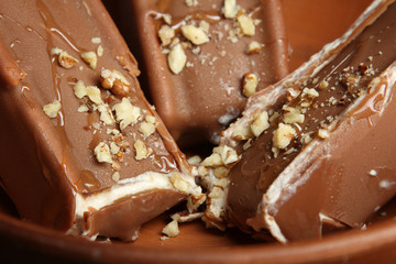 Classic chocolate ice cream with nuts in a clay plate. Close-up.