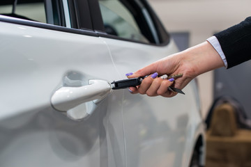 Hand holding car key in door lock