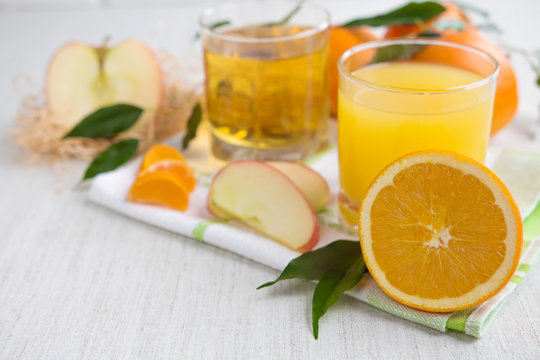 Oranges, apples and fresh juice on a light background