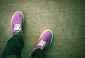 Top view of a pair of purple sneakers shoes on concrete floor background.