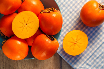 Ripe persimmons in plate on the table, top view