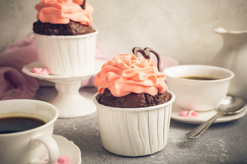 Beautiful chocolate cupcake, pink cream and heart on gray stone background. Valentines, Mother Day, wedding concept with copy space. Retro style toned.
