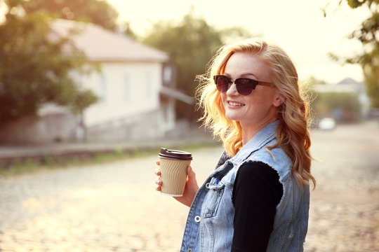 Beautiful girl with cup of coffee on street