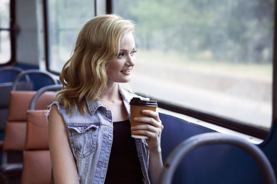 Beautiful girl with cup of coffee in trolleybus