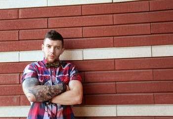 Obraz premium Young tattooed man posing on brick wall background