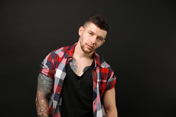Naklejka premium Young tattooed man posing on dark background