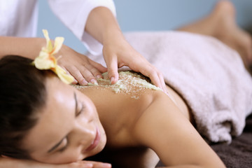 Obraz na płótnie Canvas Young woman receiving scrub massage in spa salon