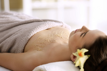 Obraz na płótnie Canvas Young woman undergoing scrub treatment in spa salon, close up view