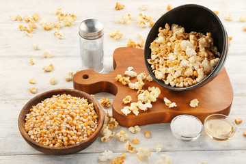 Bowls full of traditional popcorn and corn grain on wooden table
