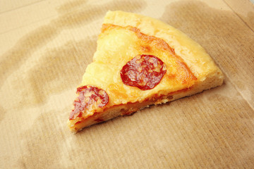 Slice of pepperoni pizza on cardboard