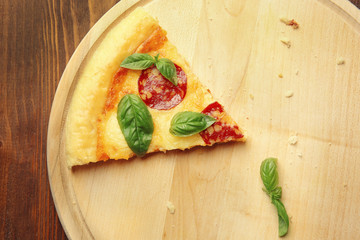 Slice of pepperoni pizza on wooden board