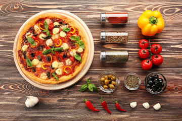 Freshly baked  pizza with ingredients on wooden table