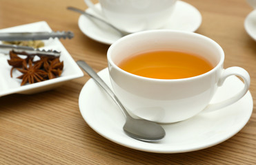 Cup of tea, saucer and spoon on wooden table, close up view