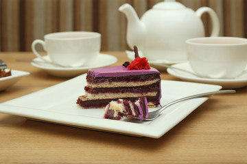 Plate with tasty cake and fork on wooden table