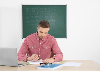 Young male teacher working in classroom