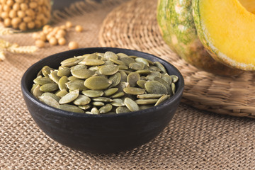 Green pumpkin seeds peeled in a black cup, snack for healthy and