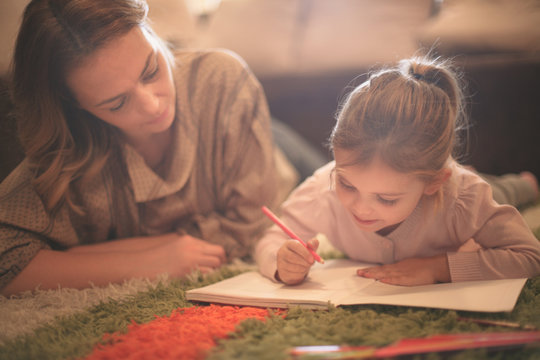 Girl drawing with her mother.