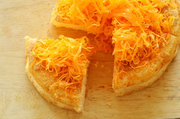 egg golden threads topping butter cake cut for piece on wooden chop block