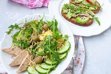 Green salad with avocado, couscous and tofu. Open sandwiches with avocado and arugula.  Love for a healthy raw food concept.