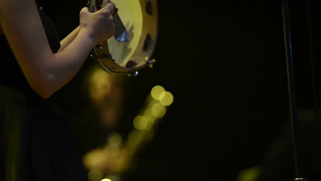 Woman plays tambourine on stage