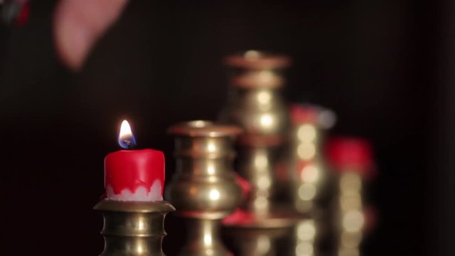 Color footage of a candle in a candlestick, and a hand lighting it with a lighter. 