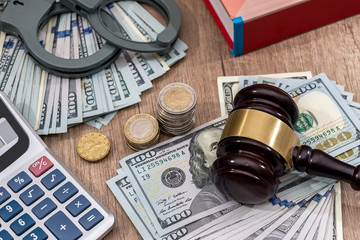 Law gavel with handcuffs, dollars and books as background, close up.