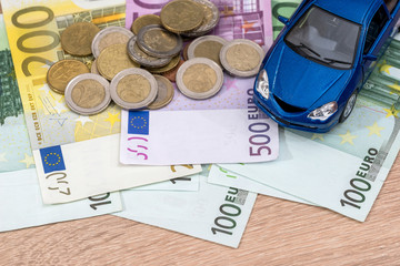 blue toy car with euro bills and coin.