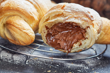 Croissant with chocolate filling on black wooden background