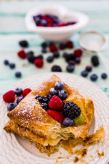 Delicious puff pastry with forest fruit on wooden table. 