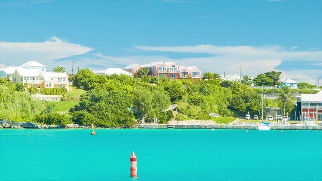 Onboard a Ferry, Sailing Through Bermuda's St. George's Harbor, Featuring Luxury Buildings and Yachts Amonst Lush Greenery and Tropical Turquoise Colored Water on a Sunny Day