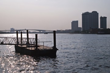 Chao Phraya river boat pier against bridge and building in evening