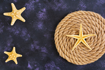 Fototapeta na wymiar Rope and starfish on dark background. Top view
