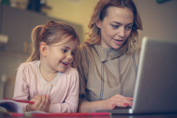 Mother with daughter using laptop.