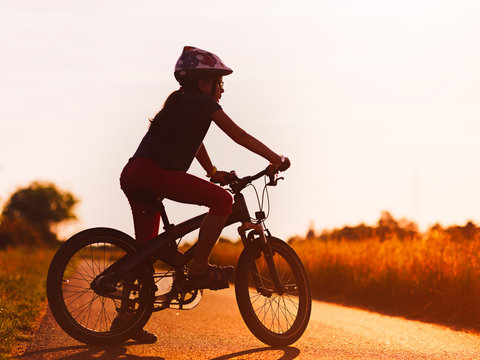 Silhouette of young girl on a mountain bicycle at sunset