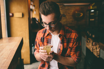 Young student is sitting in the restaurant and taste a warm drink. man drinking  tea at the cafe